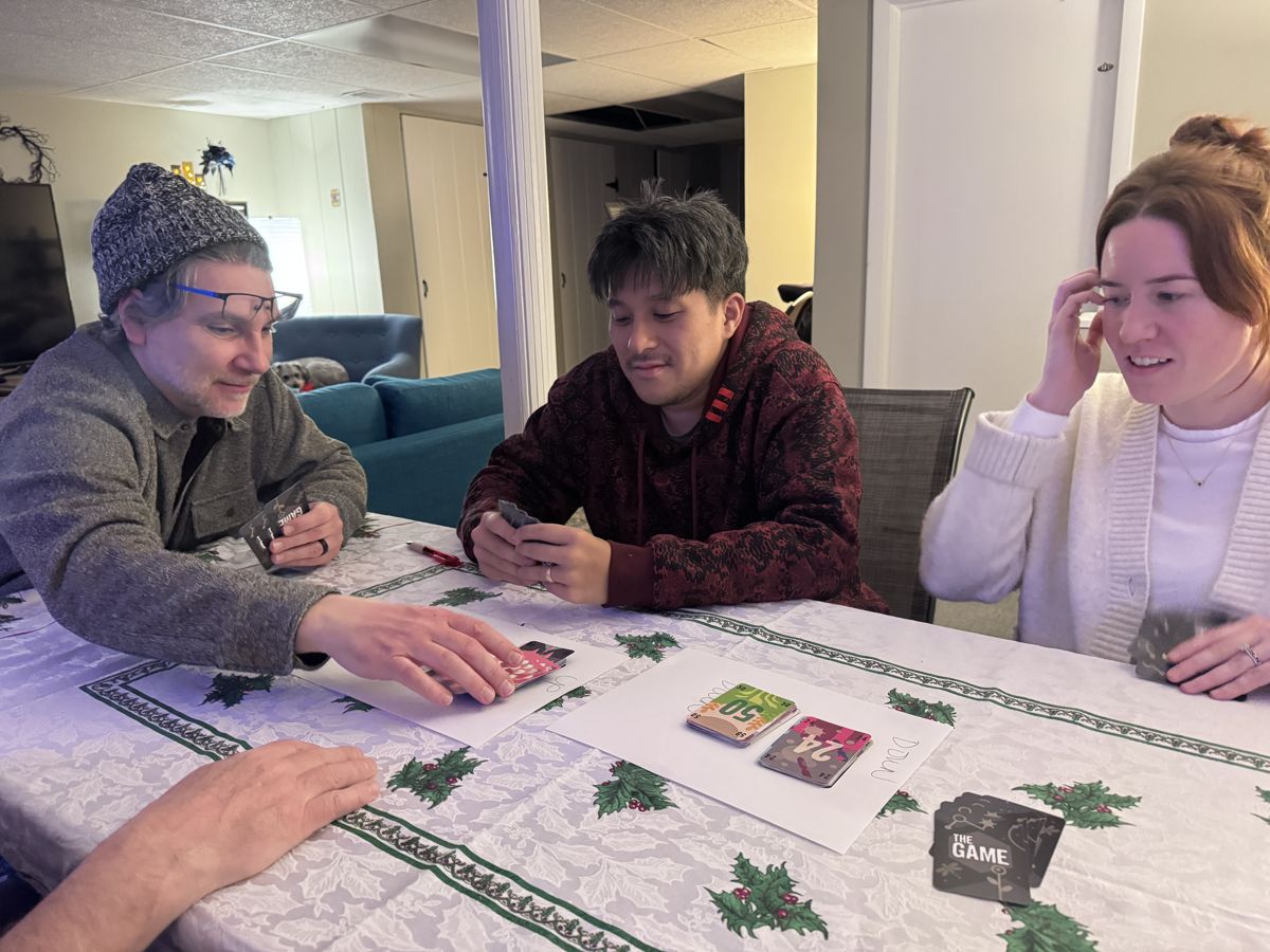 Three people laughing over a cooperative card game