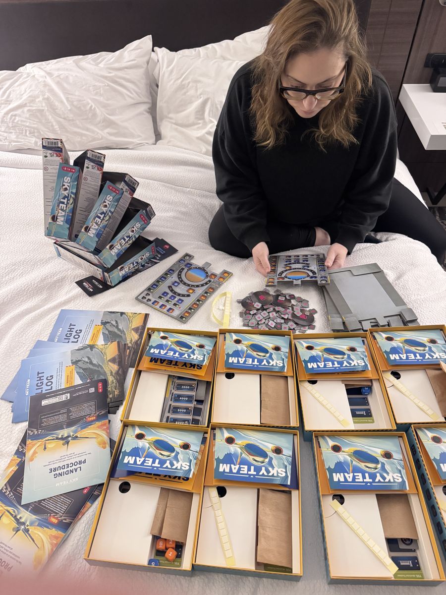 Laura prepping stacks of board games on a hotel bed