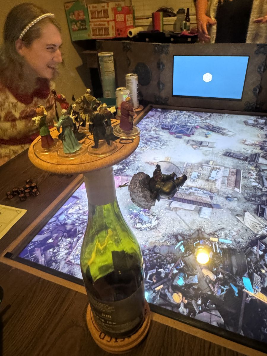 Players gathered around a digital game table covered in miniatures